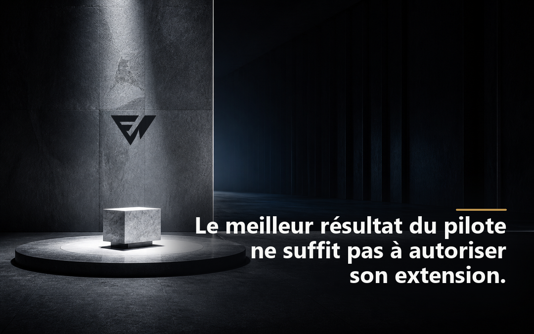 Petit module minéral éclairé sur une plateforme d’essai, devant un vaste espace architectural maintenu dans l’ombre.